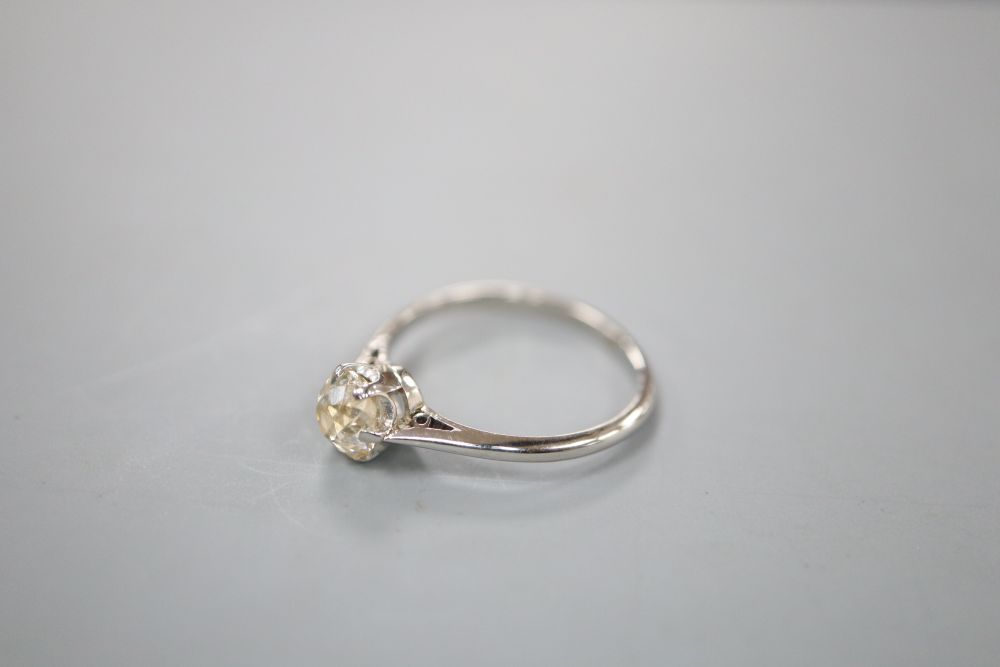 A white metal (stamped platinum) and diamond solitaire ring, size L, gross 2.4 grams.